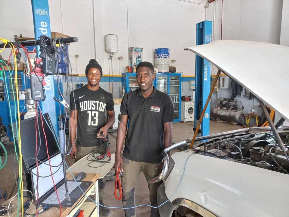 Automotive technicians working with diagnostic equipment at a training shop in Senegal